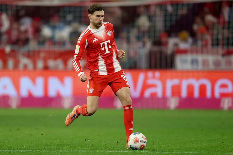 Leon Goretzka in a red Bayern Munich home kit dribbling a soccer ball on a grass pitch