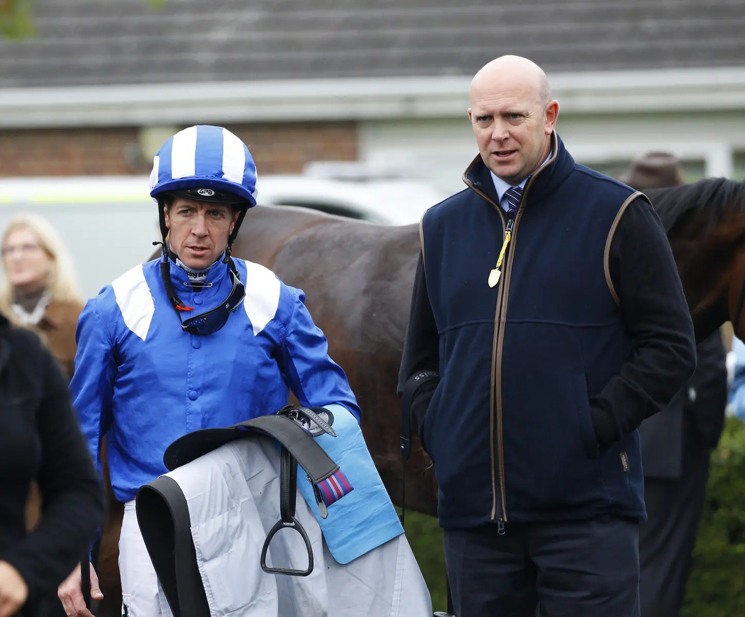 Owen Burrows standing next to a jockey in blue and white silks and a horse.