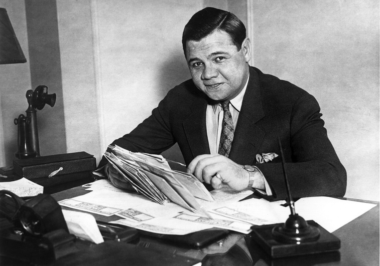 Babe Ruth sitting at a desk. 