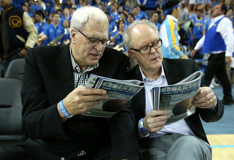 LOS ANGELES, CA - JANUARY 09: NBA coaching legend Phil Jackson (L) and actor John Lithgow consult their programs before the game between the Arizona Wildcats and the UCLA Bruins at Pauley Pavilion on January 9, 2014 in Los Angeles, California. (Photo by Stephen Dunn/Getty Images)