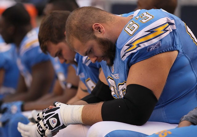 San Chargers teammates hang their heads as they sit on the sidelines.