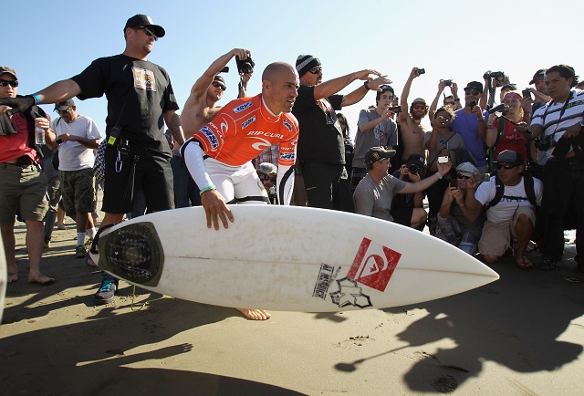 kelly slater prepares to enter the water with a surfboard kelly slater with a surfboard