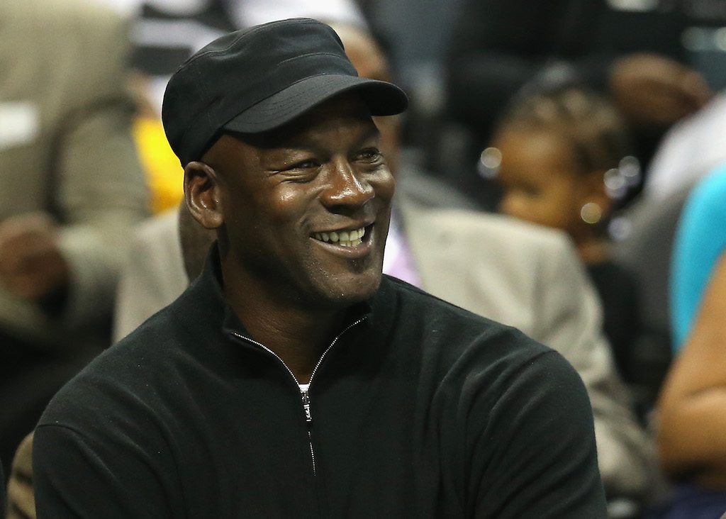 Michael Jordan smiles as he watches an NBA game court-side.