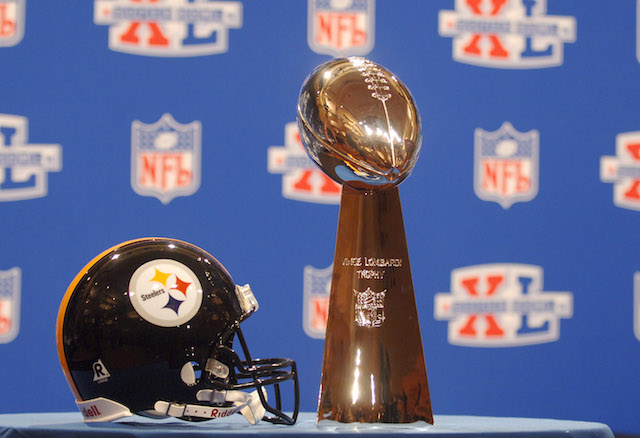 A Pittsburgh Steelers helmet and the Lombardi Trophy rest on a table before a press conference.