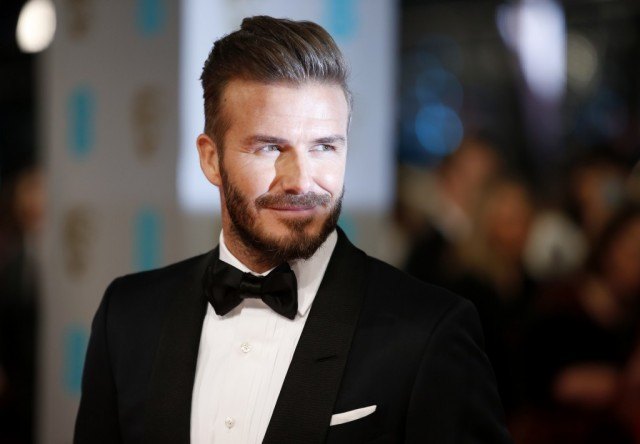 David Beckham smiles as he stands on the red carpet.