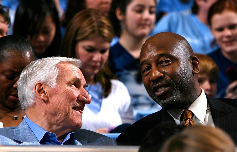 Dean Smith (L) and James Worthy (R) converse before the game.