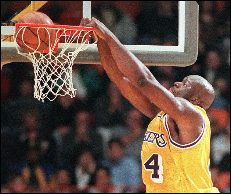 Shaquille O'Neal slam dunks the basketball.