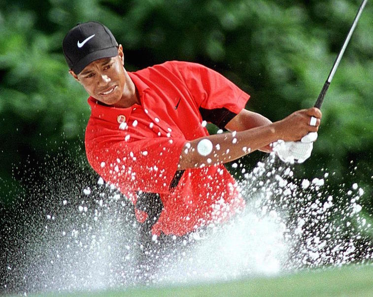 Tiger Woods chips out of the bunker on the fifth green during the Masters tournament.