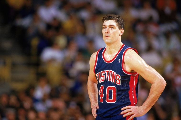 Bill Laimbeer stands on the court with his hands on his hips.