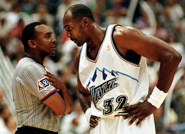 Karl Malone puts his hands on his hips and looks down at the referee.