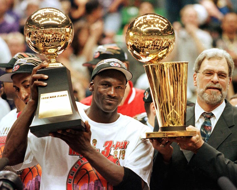 Michael Jordan and Phil Jackson hold the trophies.