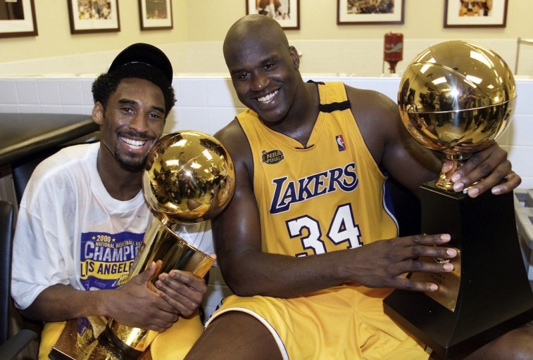Kobe Byrant and Shaquille O'Neal pose together with trophies.