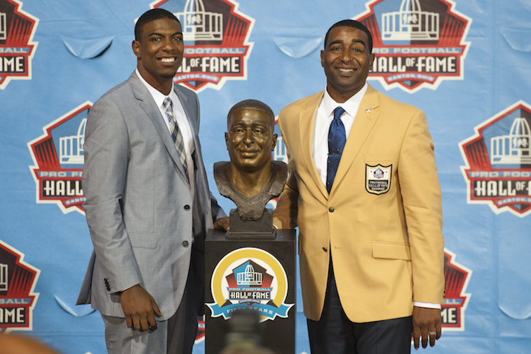 Duron Carter, left, presents his father and former Minnesota Vikings receiver Chris Carter, right, with his Hall of Fame bust during the NFL Class of 2013 Enshrinement Ceremony.