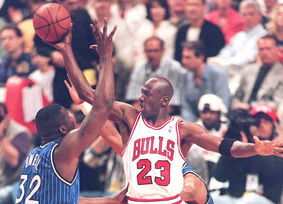 Michael Jordan makes a face at an opposing team member as he looks to shoot the ball.