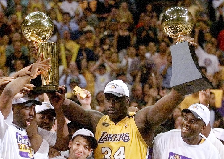 Shaq raises both the Larry O'Brien trophy and his MVP trophy after winning the 2000 championship.