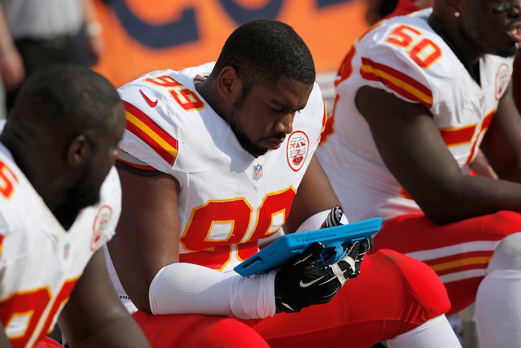 Vance Walker #99 of the Kansas City Chiefs consults a person electronic device