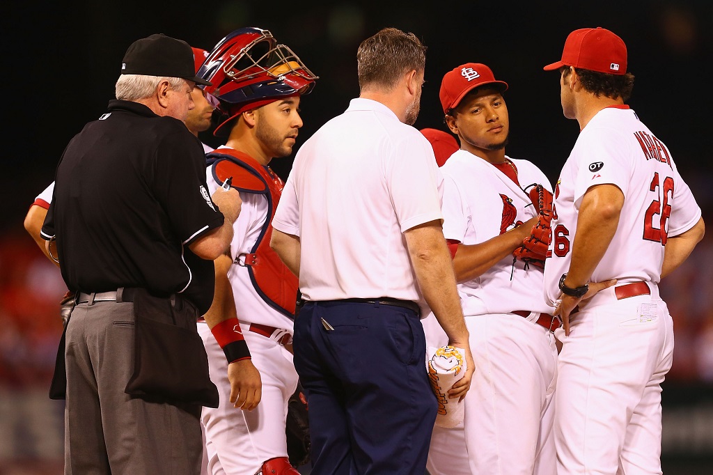 ST. LOUIS, MO - SEPTEMBER 25: Starter Carlos Martinez #18 of the St. Louis Cardinals meets with manager Mike Matheny #26 and a member of the training staff in the first inning against the Milwaukee Brewers at Busch Stadium on September 25, 2015 in St. Louis, Missouri. Martinez was removed from the game with shoulder tightness.