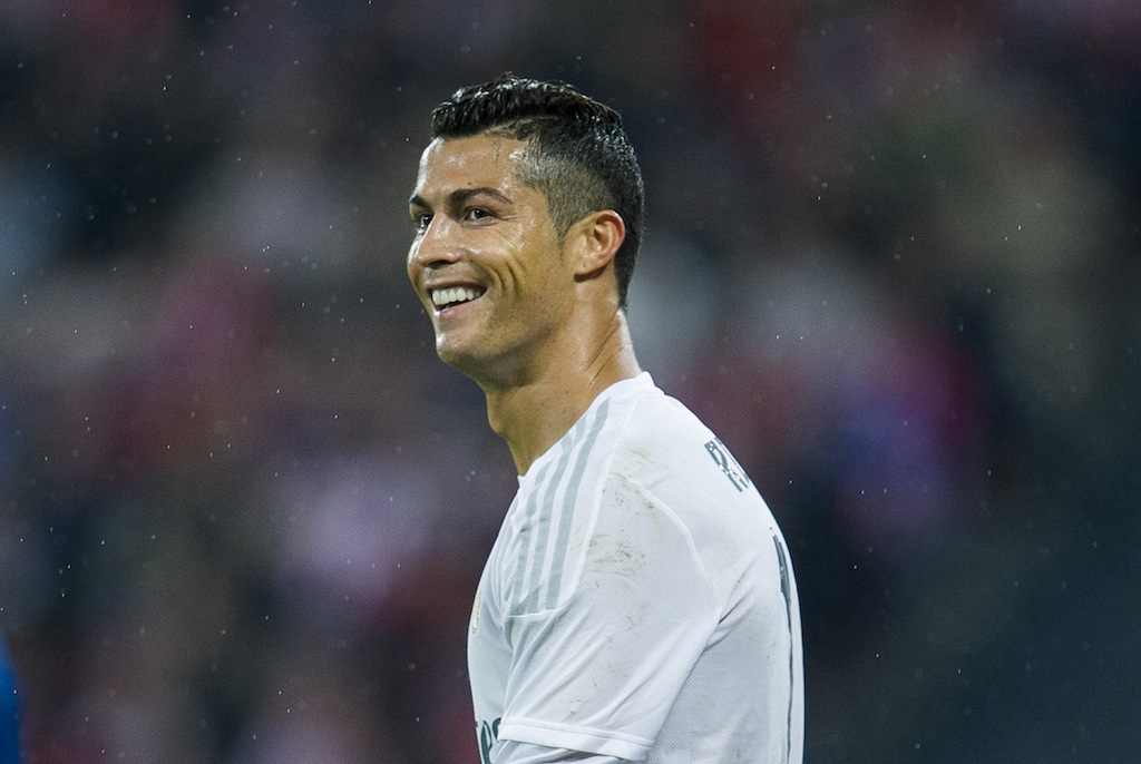 Cristiano Ronaldo beams as he walks across the field in the rain.