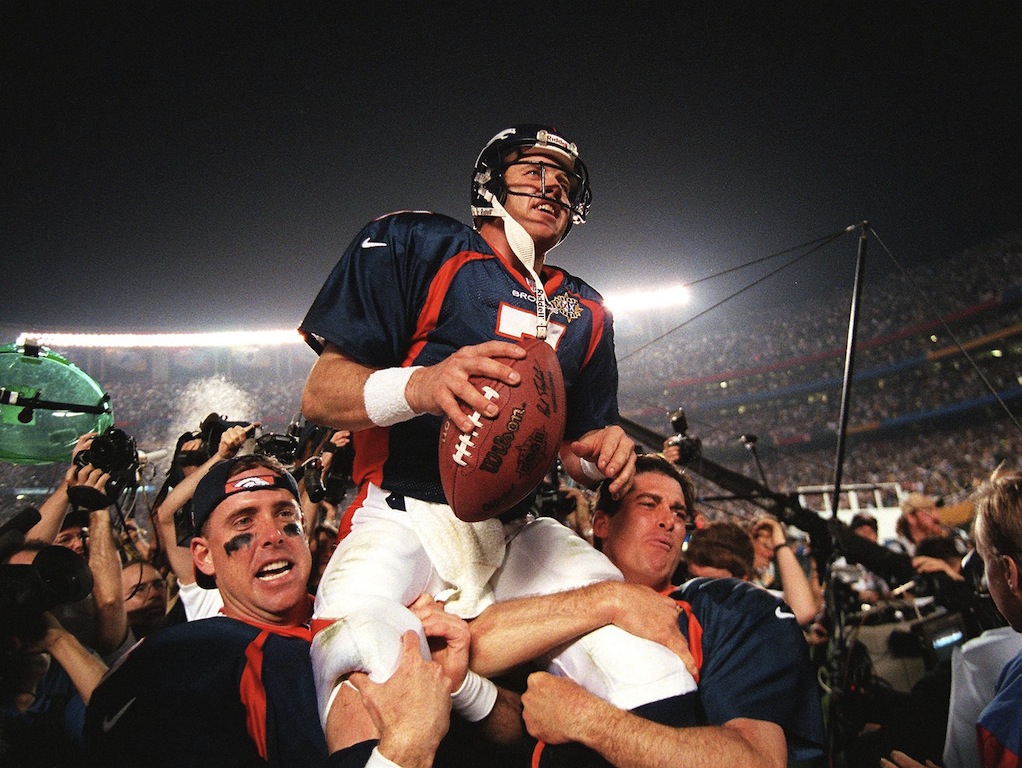 John Elway's teammates hoist him in the air after winning the Super Bowl MVP in his final game.