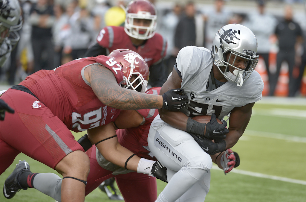Royce Freeman #21 of the Oregon Ducks is tackled by nose tackle Robert Barber #92 of the Washington State 