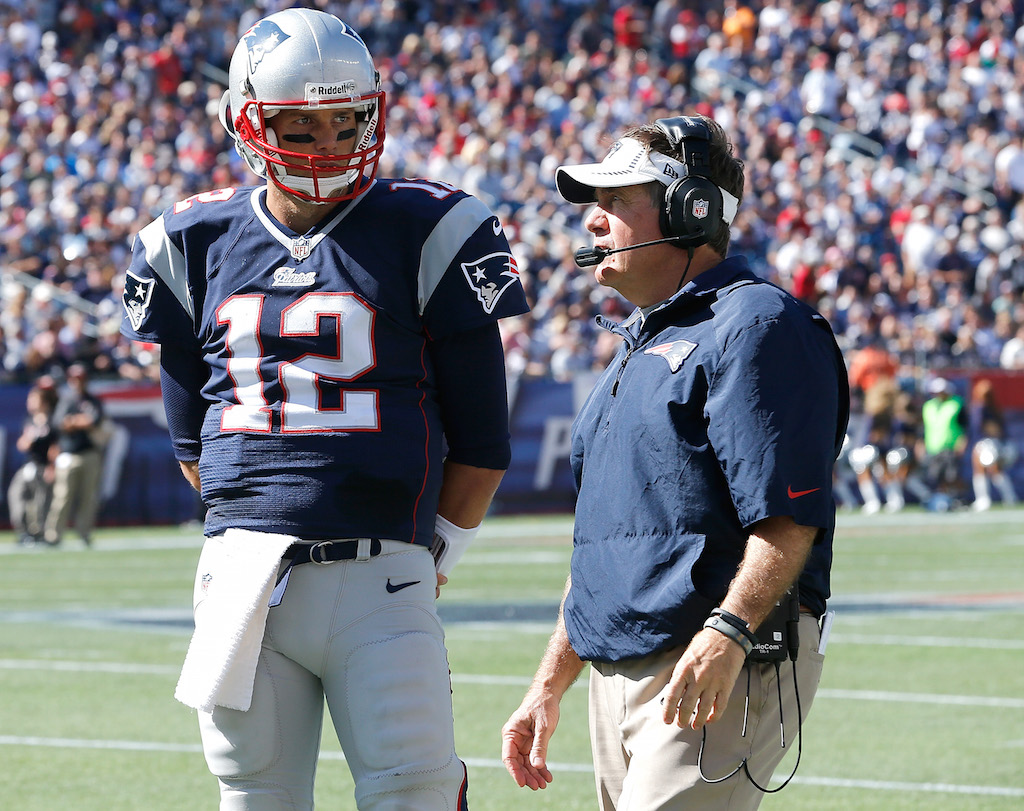Tom Brady and Bill Belichick stand on the field together.