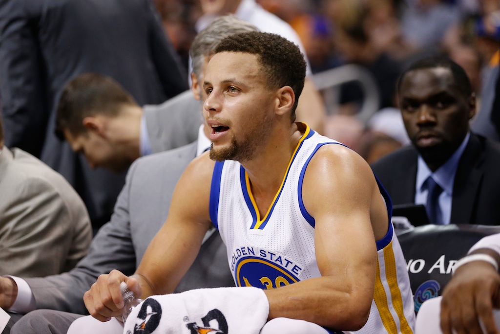 Stephen Curry smiles on the bench