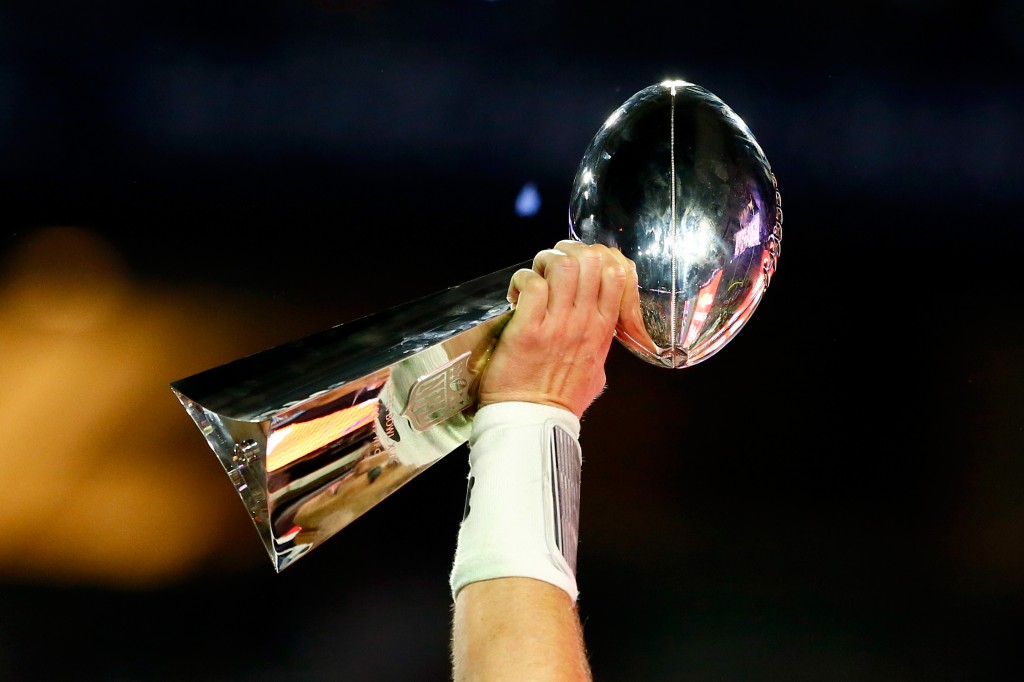 The Super Bowl Lombardi Trophy is hoisted in the air.