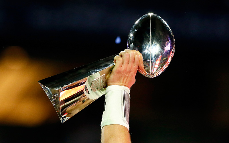The Lombardi Trophy is raised high in the air.