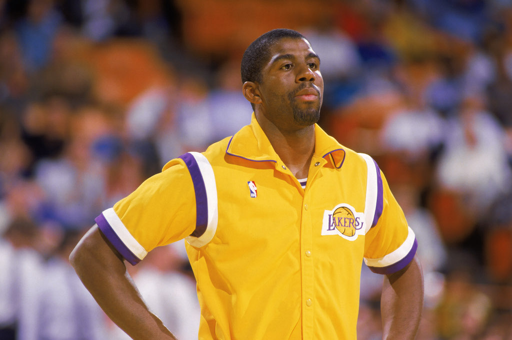 Magic Johnson waits on the sideline prior to the start of a game.