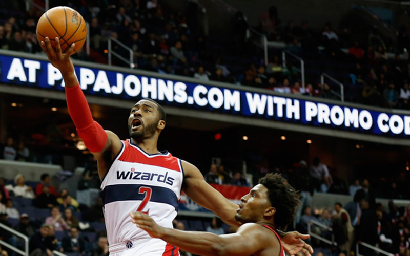 John Wall attempts to shoot the ball while fending off an opposing team member.