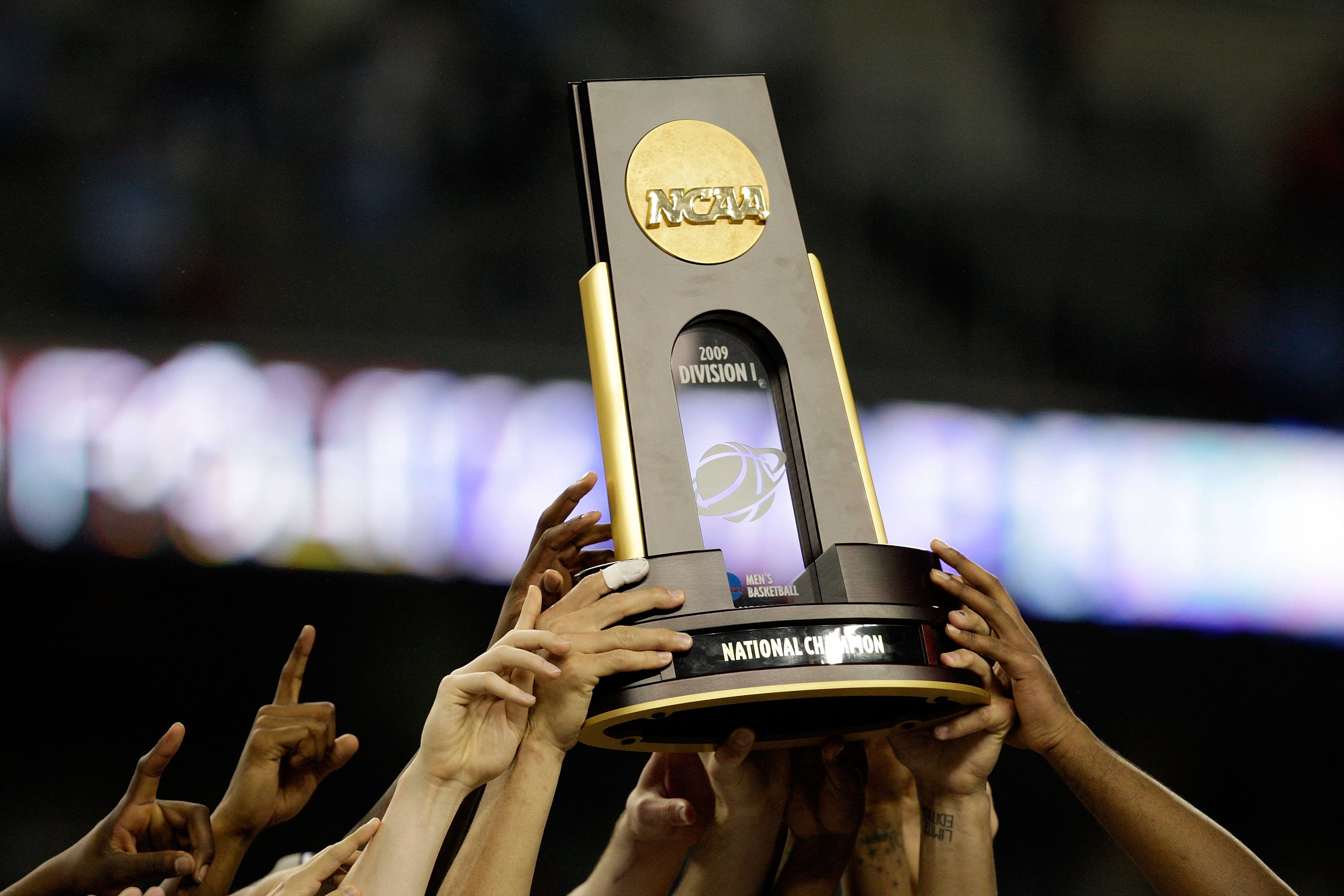 The NCAA National Championship trophy is hoisted in the air.