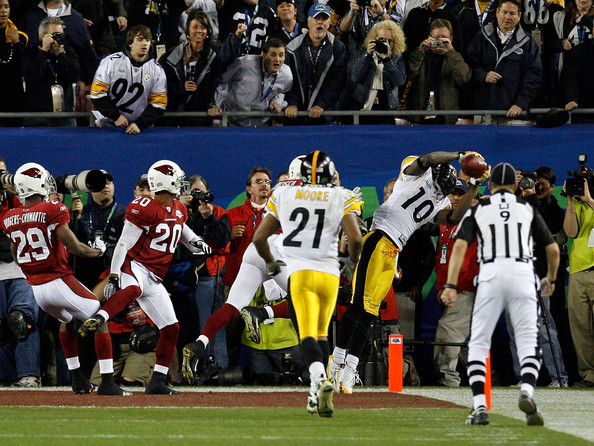 Santonio Holmes grips the football as he lands in the end zone.