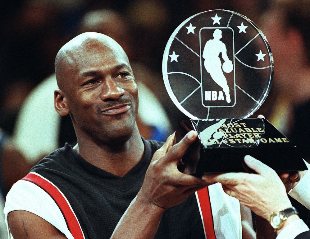 Michael Jordan holds the MVp All Star Game trophy.