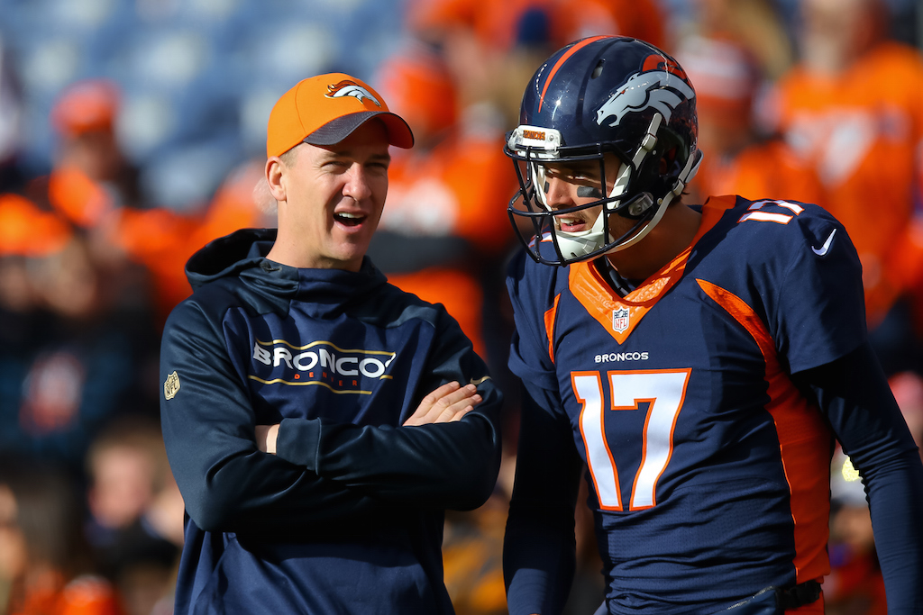 Injured quarterback Peyton Manning of the Denver Broncos speaks with quarterback Brock Osweiler.