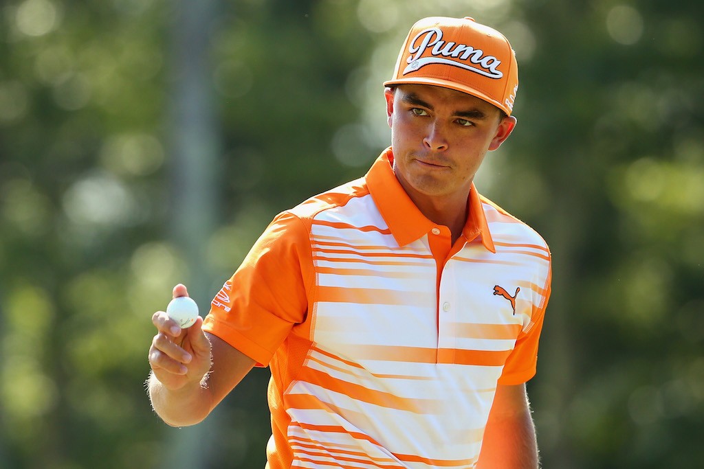 Rickie Fowler holds the ball as he walks across the green.