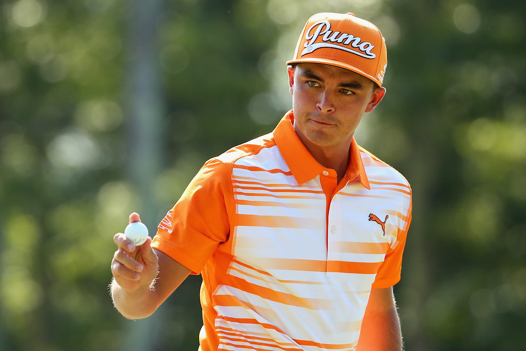 Rickie Fowler holds the ball as he walks across the green.