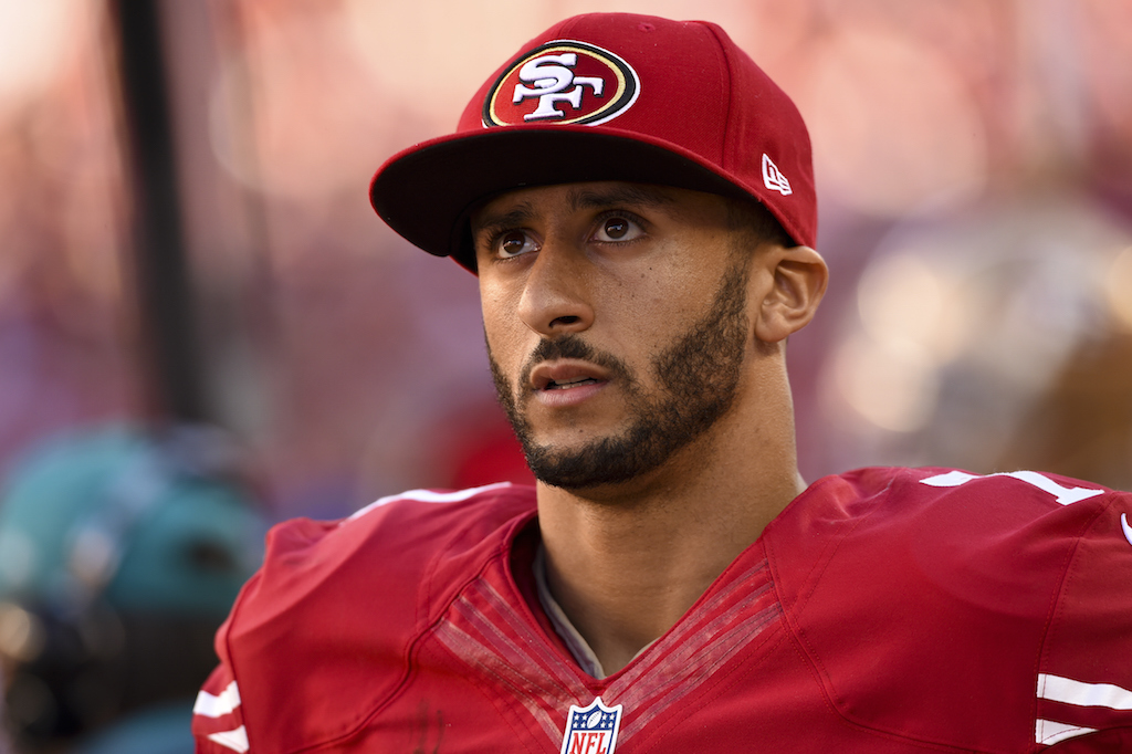 Colin Kaepernick stands on the sidelines during a game.