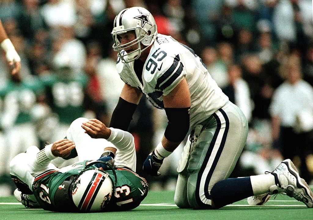 Dallas Cowboys defensive tackle Chad Hennings (R) puts Miami Dolphins quarteback (L) on the ground during first half action at Texas Stadium 25 November 1999 in Irving, Texas. The Cowboys shut out the Dolphins 20-0.