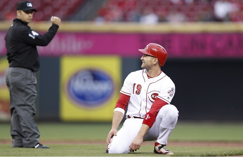Joey Votto grimaces as he kneels on the field.