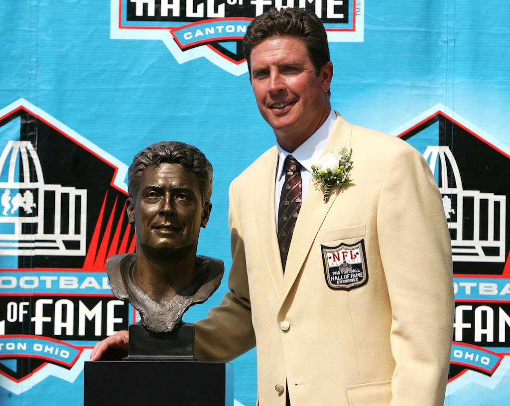 Dan Marino poses next to his Hall of Fame bust.