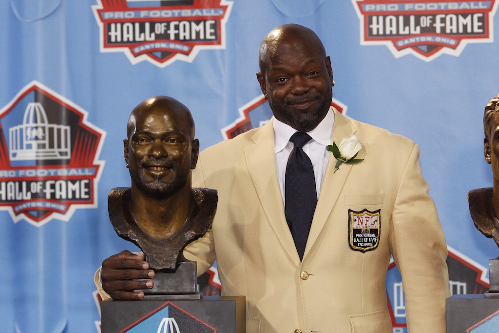 Emmitt Smith stands next to his bust in the Hall of Fame.