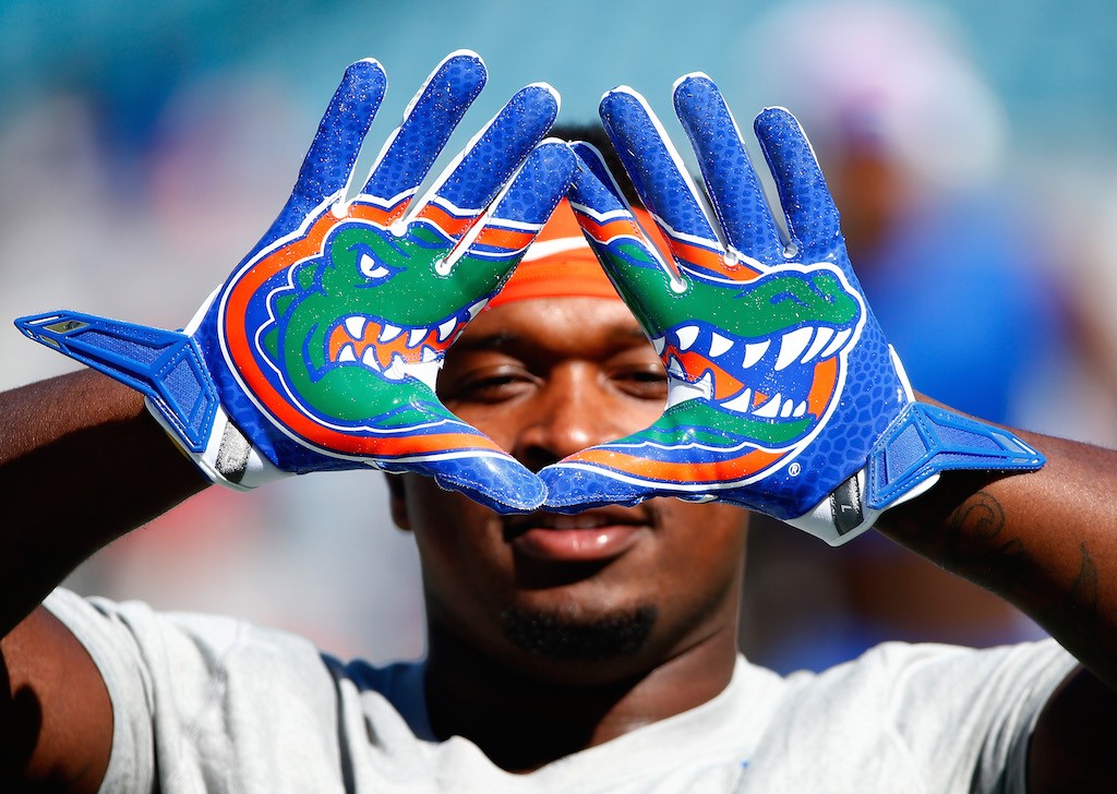 A Gators football player holds up his gloves, which have alligators on them.