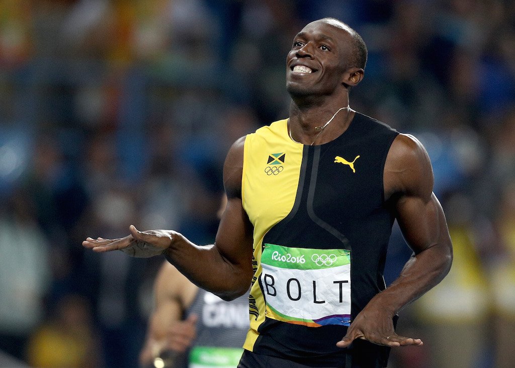 Usain Bolt smiles after crossing the finish line.
