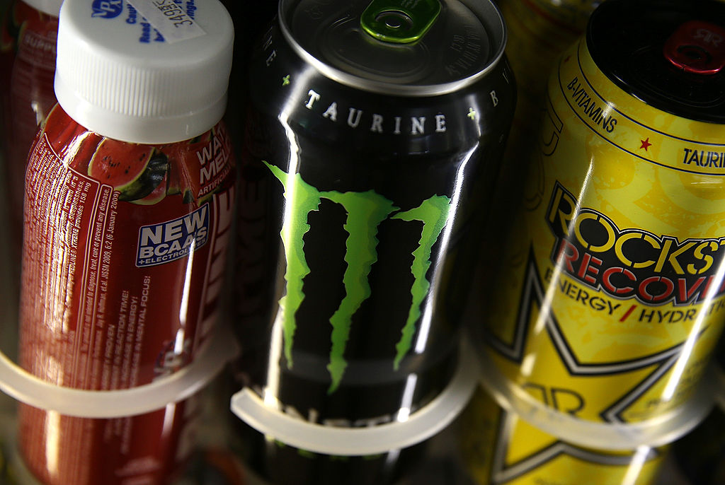 Cans of energy drinks are displayed on a shelf at a convenience store.