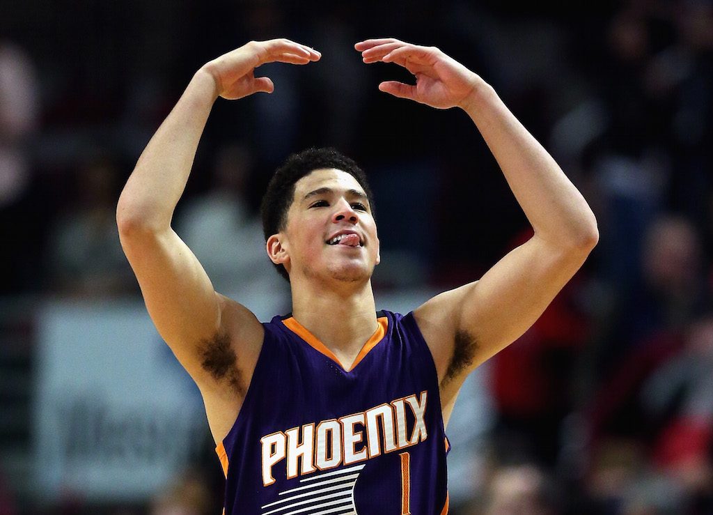 Devin Booker waves his arms to pump up the crowd.