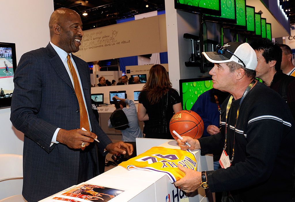 Former NBA basketball player James Worthy (L) signs autographs