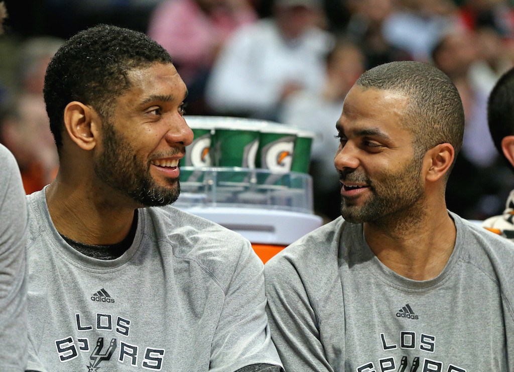 Tim Duncan and Tony Parker smiles while they sit on the bench.