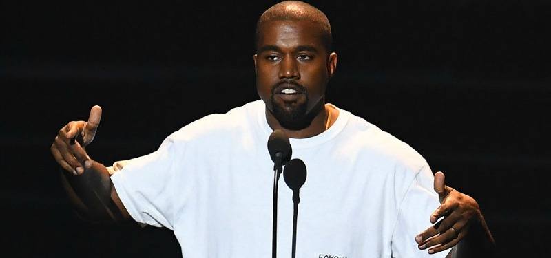 Kanye West in white t-shirt speaking into a microphone