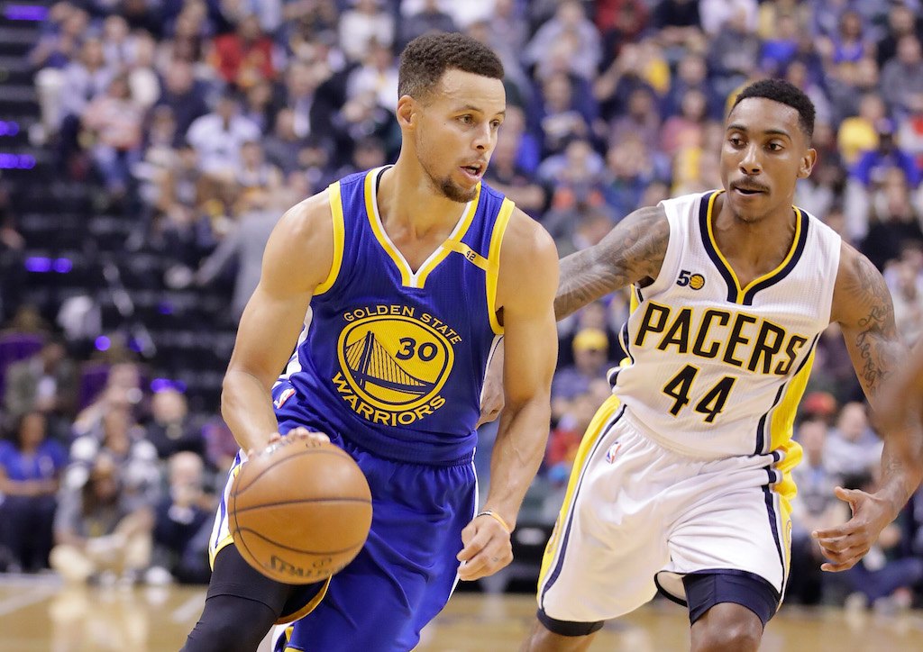 Stephen Curry drives the ball down the court past an opposing team member
