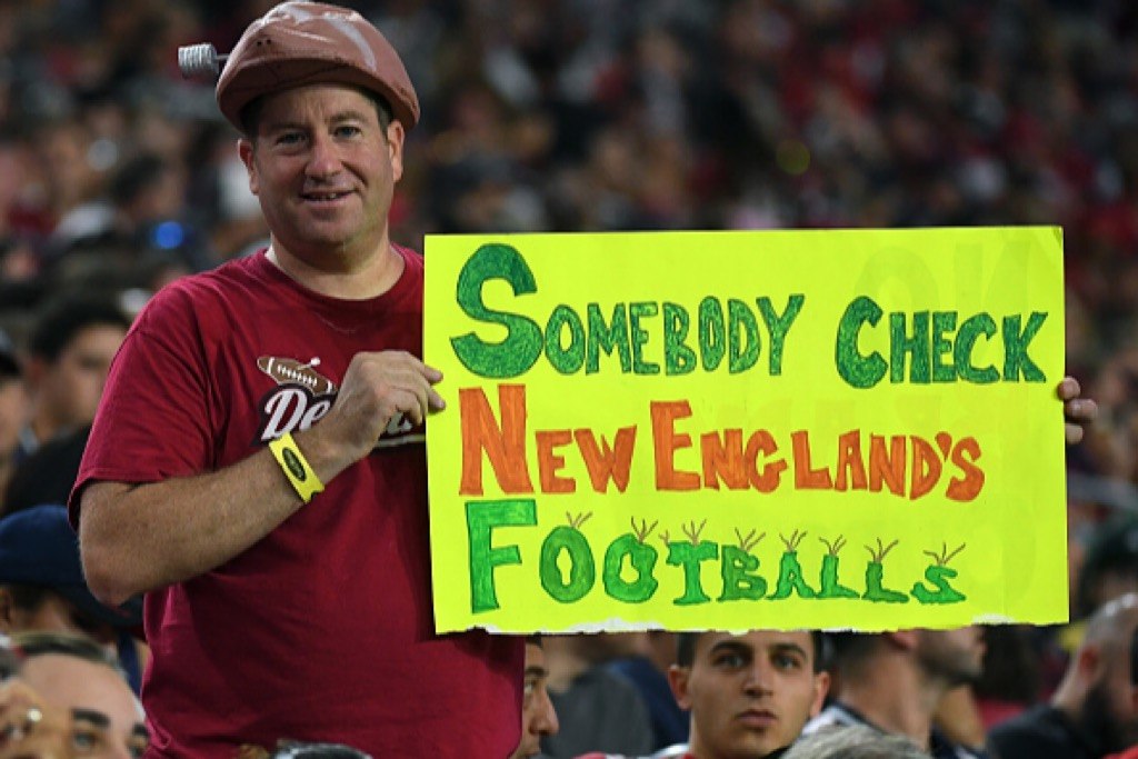 An Arizona Cardinals fan wearing a deflated football hat holds up a sign referencing Deflategate during the team's game against the New England Patriots | Ethan Miller/Getty Images